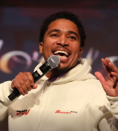 John Doe laughing on stage with a microphone