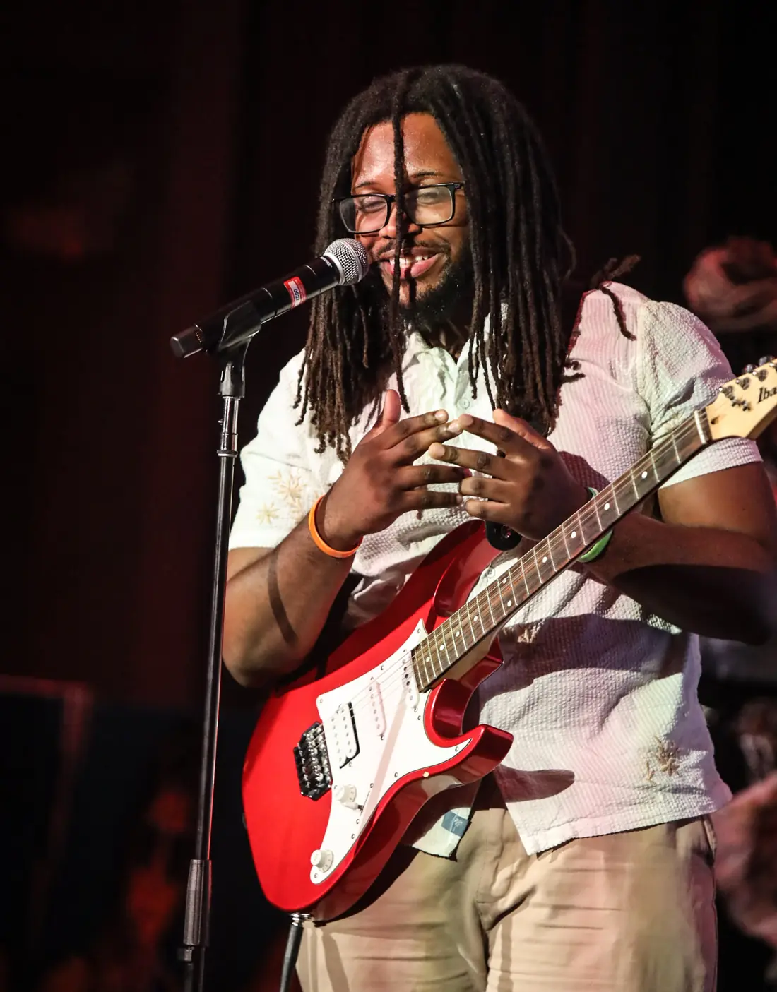 A guitarist smiling between lines at the mic