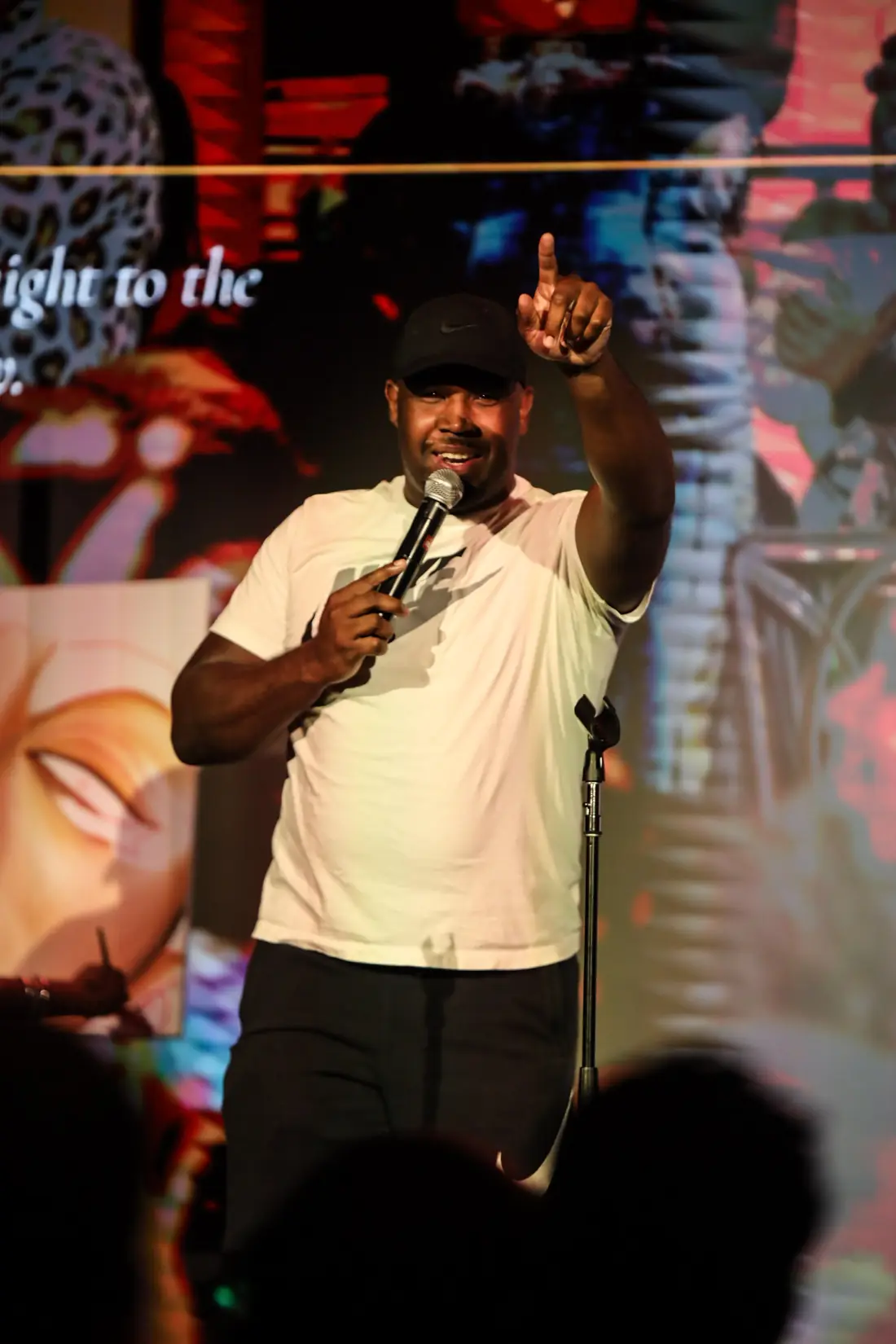 A performer in a white tee pointing up toward the crowd mid-set