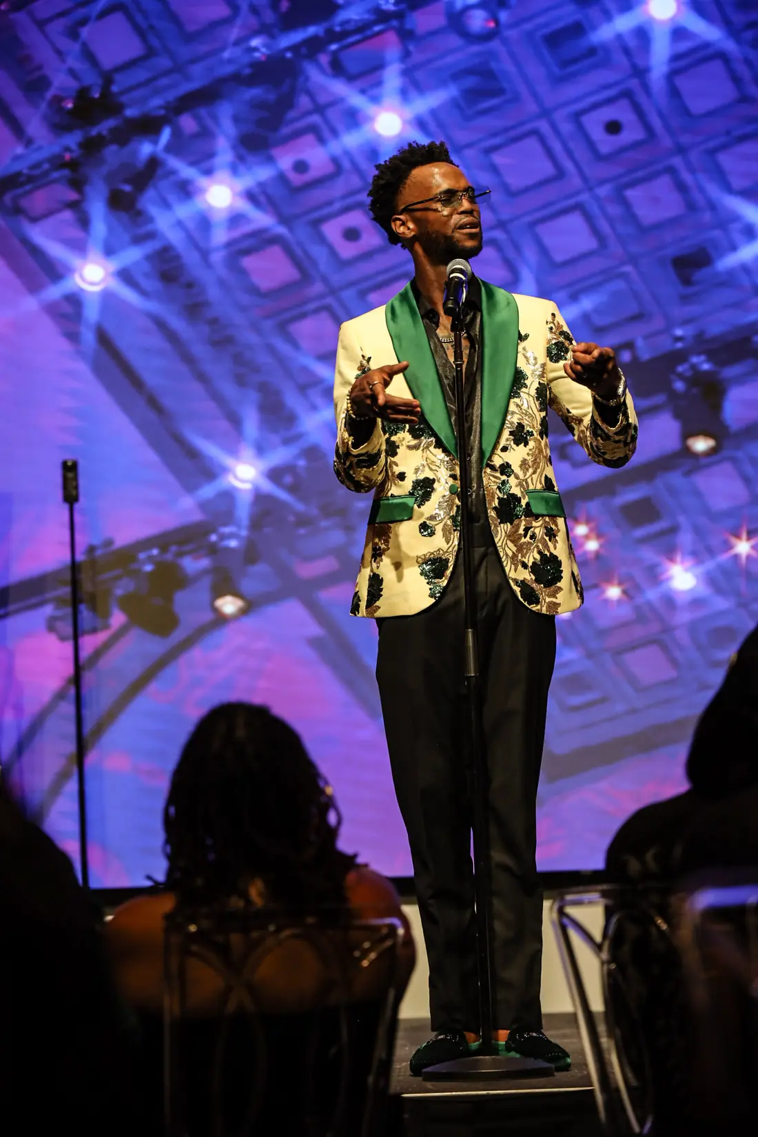A performer in a patterned jacket on a blue-lit stage
