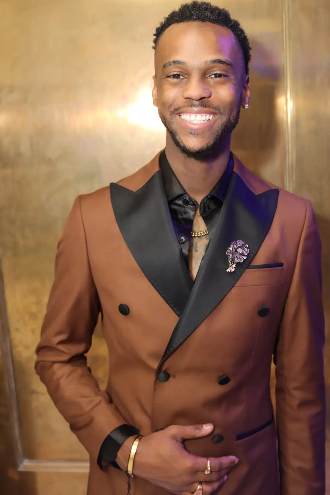 HeyTyce in a brown double-breasted suit, smiling